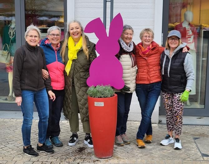 Sechs der Stadtverschönererinnen versammeln sich zum Gruppenfoto um einen frisch bepflanzten roten Kübel